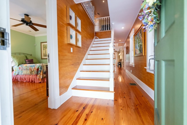 stairway with baseboards, a ceiling fan, wood-type flooring, crown molding, and recessed lighting