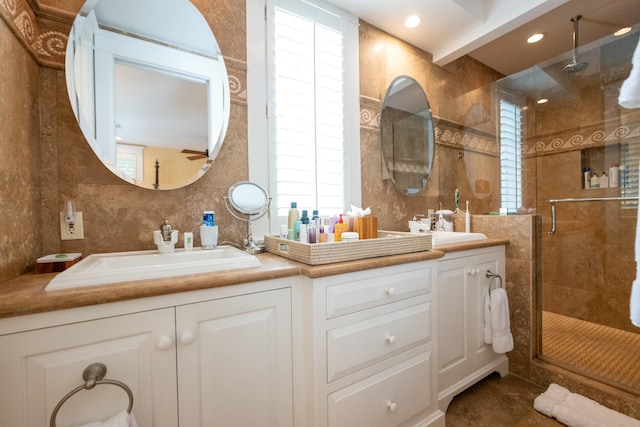 full bath featuring double vanity, a shower stall, tile walls, and a sink