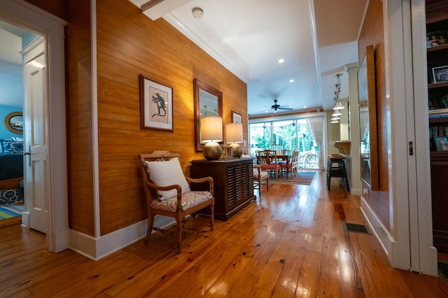 corridor with wood walls, baseboards, visible vents, and hardwood / wood-style floors