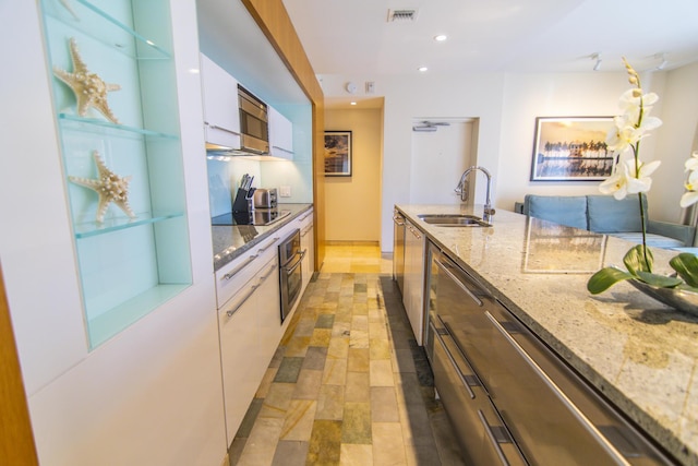 kitchen featuring white cabinetry, appliances with stainless steel finishes, sink, and light stone counters