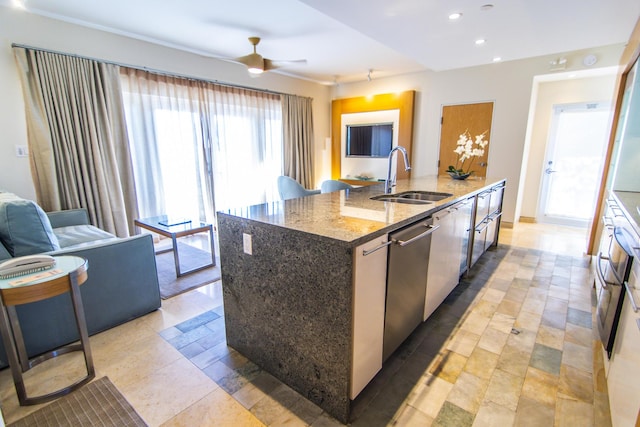 kitchen with stone counters, dishwasher, sink, a kitchen island with sink, and ceiling fan