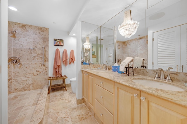 bathroom featuring an inviting chandelier, a sink, a tile shower, and double vanity