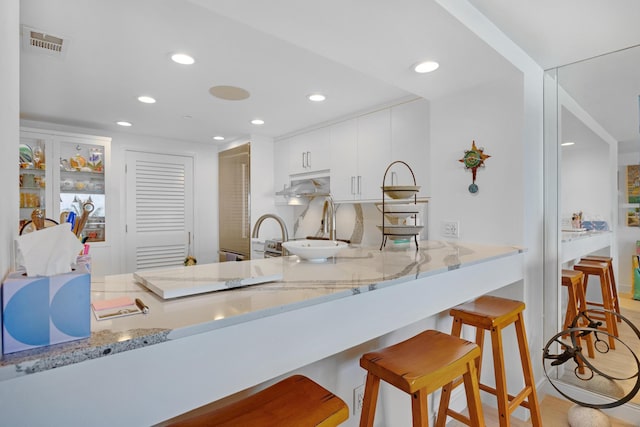 kitchen with visible vents, recessed lighting, white cabinetry, and light stone counters