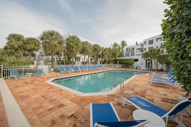 community pool with fence and a patio