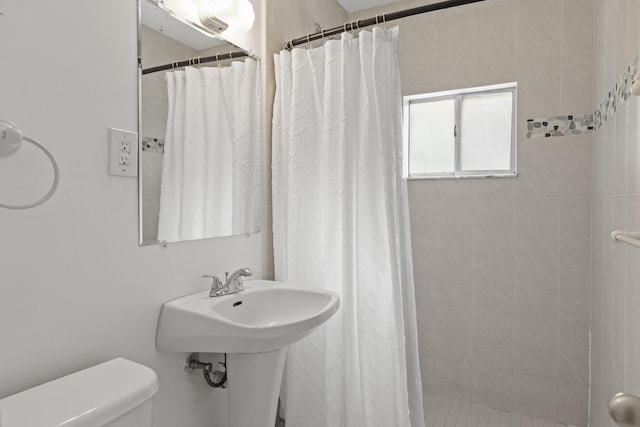 bathroom with toilet, sink, and a shower with curtain