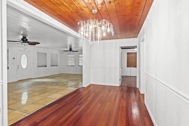 unfurnished dining area with ceiling fan with notable chandelier, hardwood / wood-style flooring, wood ceiling, and baseboards