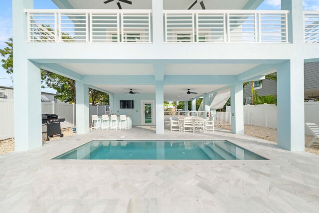 view of pool featuring an outdoor bar, ceiling fan, area for grilling, and a patio area