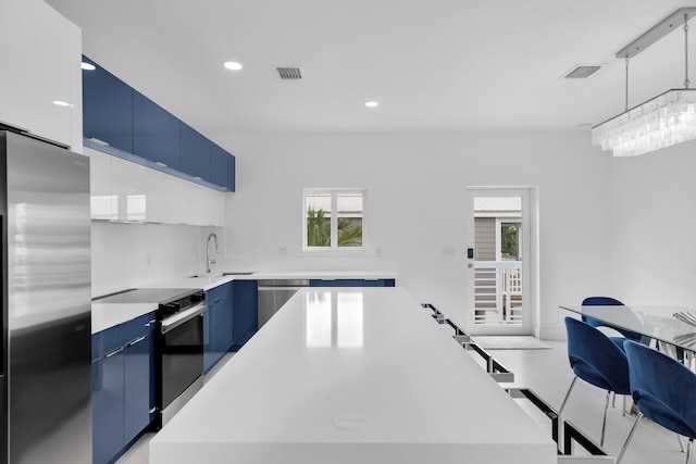 kitchen with blue cabinets, a kitchen bar, a kitchen island, and appliances with stainless steel finishes