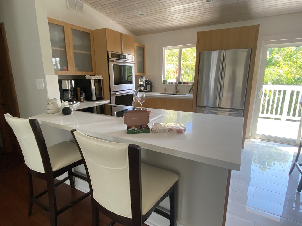 kitchen featuring stainless steel appliances, sink, a kitchen bar, and kitchen peninsula