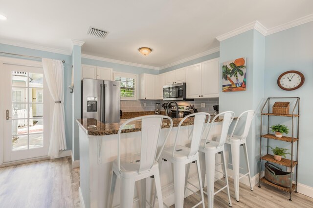 532 Porter Ln, Key West, FL 33040 - kitchen featuring appliances with stainless steel finishes, baseboards, light wood-style floors, a kitchen breakfast bar, and tasteful backsplash