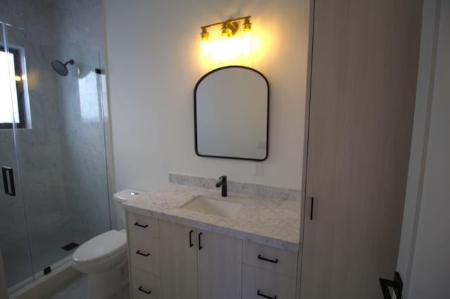 bathroom featuring vanity, an enclosed shower, and toilet