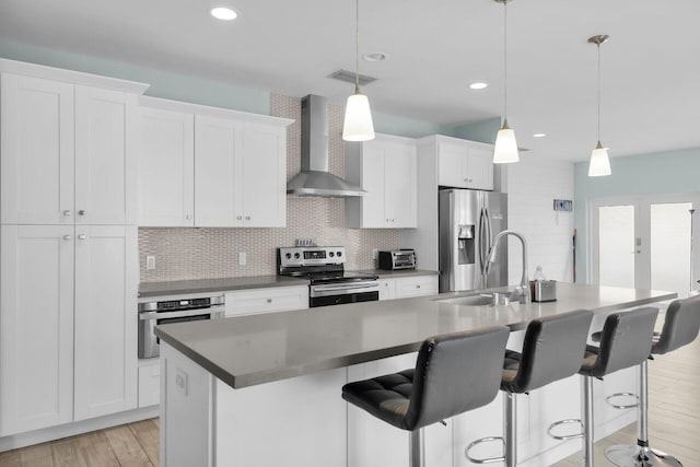 241 W Seaview Dr, Duck, FL 33050 - kitchen with stainless steel appliances, wall chimney exhaust hood, a kitchen island with sink, a sink, and light wood finished floors