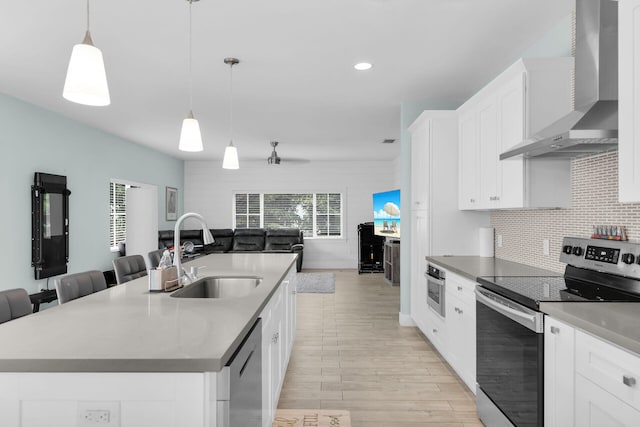 241 W Seaview Dr, Duck, FL 33050 - kitchen featuring appliances with stainless steel finishes, wall chimney exhaust hood, open floor plan, a sink, and light wood-style flooring