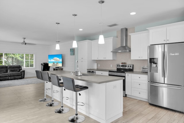 241 W Seaview Dr, Duck, FL 33050 - kitchen with stainless steel appliances, wall chimney exhaust hood, open floor plan, a kitchen breakfast bar, and light wood-type flooring