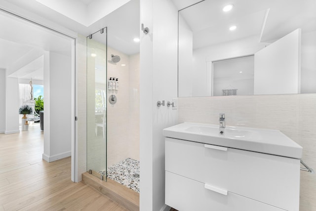 bathroom with an enclosed shower, vanity, wood-type flooring, and tasteful backsplash