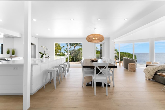 dining room featuring a water view, plenty of natural light, and light hardwood / wood-style flooring