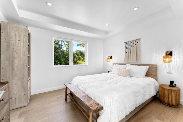 bedroom featuring light hardwood / wood-style flooring and a tray ceiling