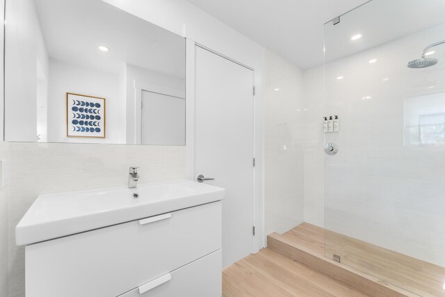 bathroom with vanity, hardwood / wood-style floors, and tiled shower