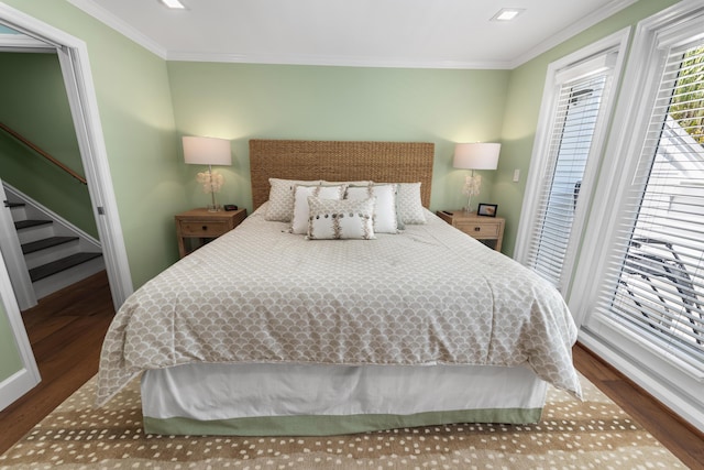 bedroom with ornamental molding and wood finished floors