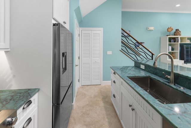 kitchen with stone countertops, a sink, white cabinetry, stainless steel fridge with ice dispenser, and crown molding