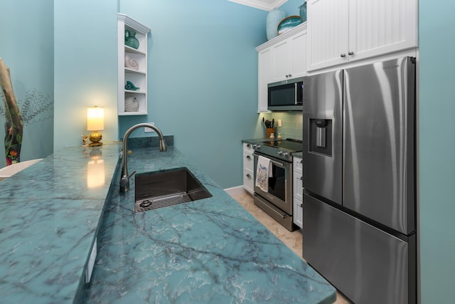 kitchen with tasteful backsplash, stainless steel appliances, stone counters, white cabinetry, and a sink