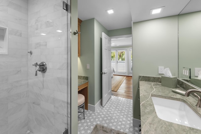 bathroom featuring a tile shower, vanity, and baseboards