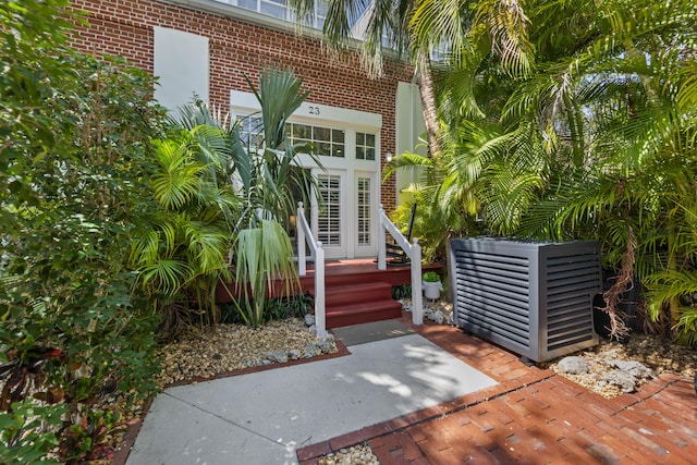 entrance to property with central AC unit and brick siding