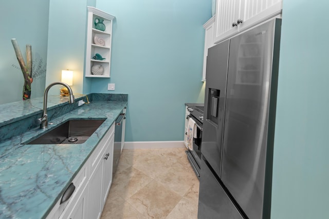 kitchen with appliances with stainless steel finishes, stone countertops, a sink, and white cabinetry