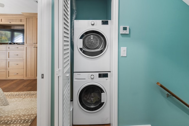 laundry room featuring stacked washer and dryer, wood finished floors, and laundry area