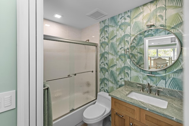 bathroom featuring enclosed tub / shower combo, vanity, toilet, and wallpapered walls