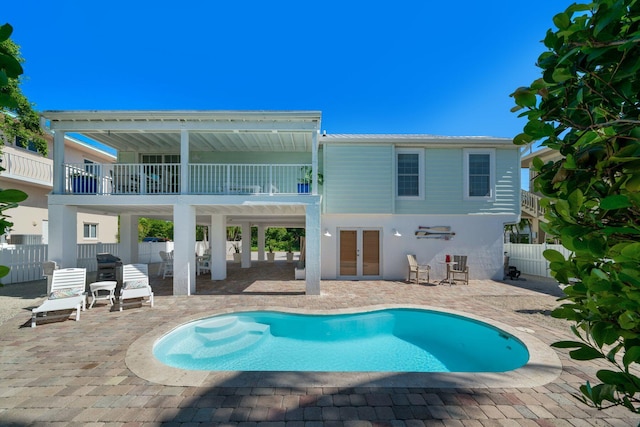 back of house with a fenced in pool, a patio, a balcony, and french doors