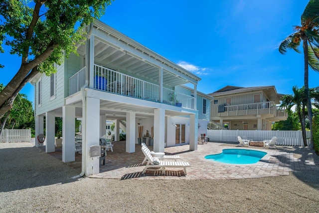 rear view of house featuring a fenced in pool, a patio area, and a balcony