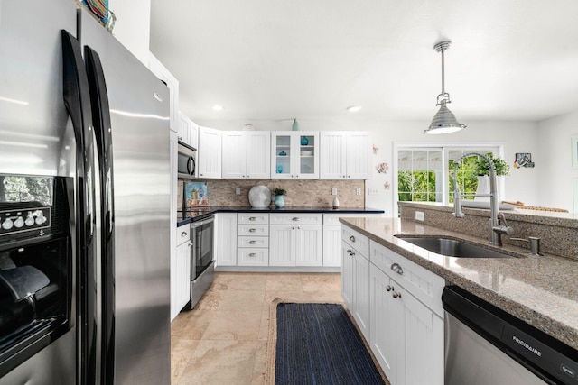 kitchen with sink, white cabinetry, stainless steel appliances, decorative light fixtures, and dark stone counters