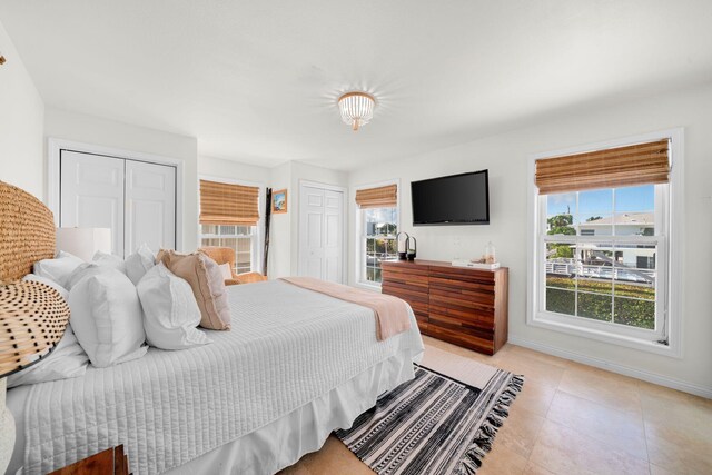 bedroom with light tile patterned floors, multiple windows, and two closets