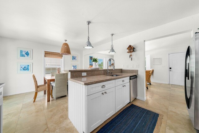 kitchen with pendant lighting, a wealth of natural light, white cabinetry, sink, and stainless steel appliances