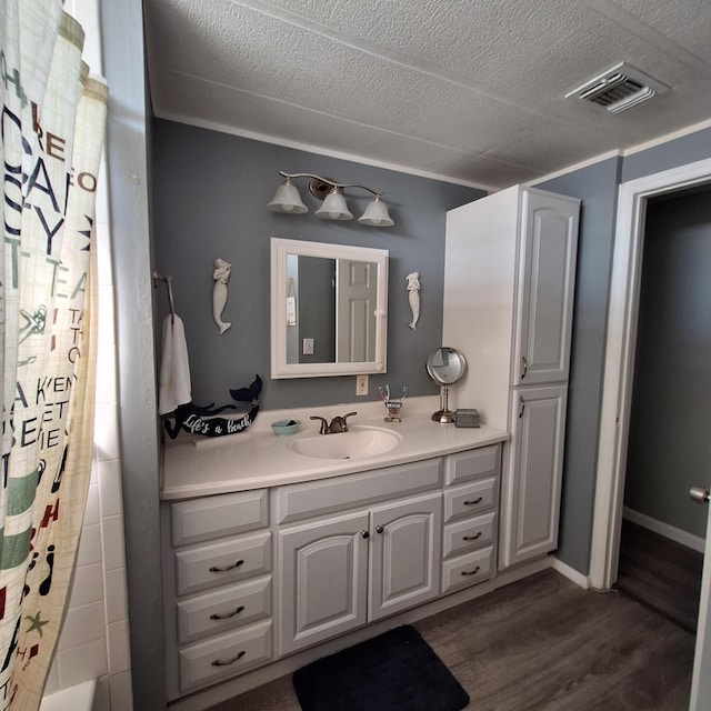 bathroom featuring vanity, hardwood / wood-style floors, shower / bath combo, and a textured ceiling