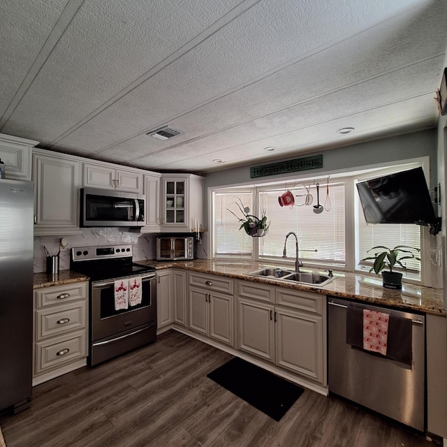 kitchen featuring sink, dark wood-type flooring, appliances with stainless steel finishes, white cabinetry, and light stone counters