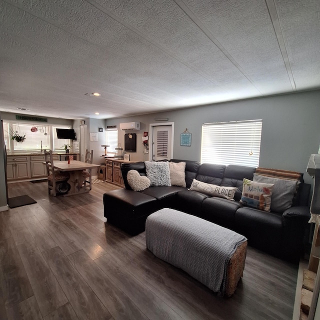 living room featuring a wall mounted AC, hardwood / wood-style floors, and a textured ceiling