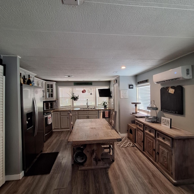 kitchen with appliances with stainless steel finishes, dark hardwood / wood-style floors, a wealth of natural light, and an AC wall unit