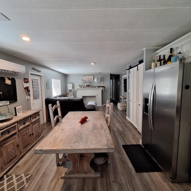 dining space featuring hardwood / wood-style flooring, a barn door, a textured ceiling, and a wall unit AC