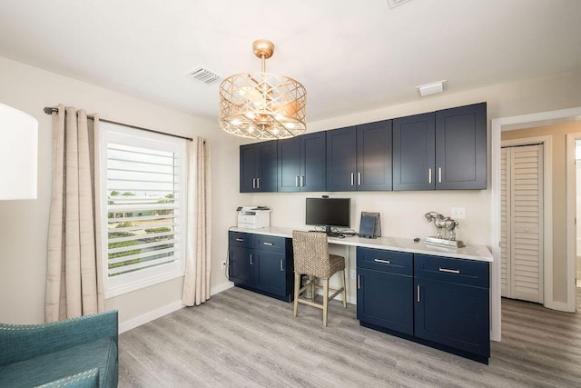 kitchen featuring pendant lighting, light hardwood / wood-style floors, built in desk, and blue cabinetry