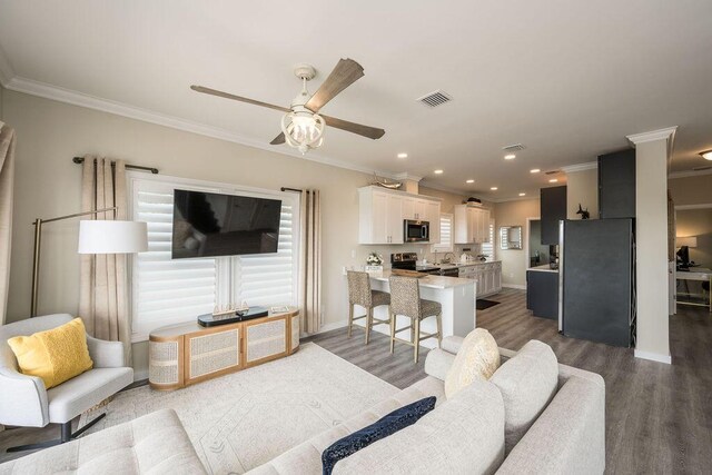 living room featuring dark wood-type flooring, ceiling fan, and ornamental molding