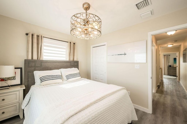 bedroom with a notable chandelier, dark hardwood / wood-style flooring, and a closet