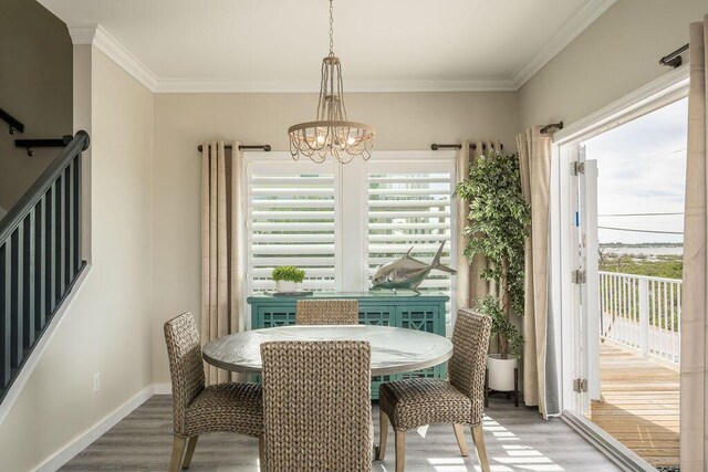 dining area featuring hardwood / wood-style flooring, ornamental molding, and a notable chandelier