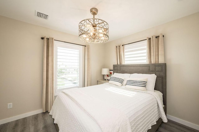 bedroom featuring multiple windows, dark wood-type flooring, and a chandelier