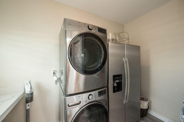 clothes washing area featuring stacked washer / dryer and wood-type flooring