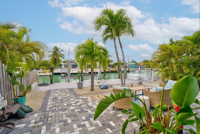 surrounding community featuring a water view, a boat dock, fence, and a patio