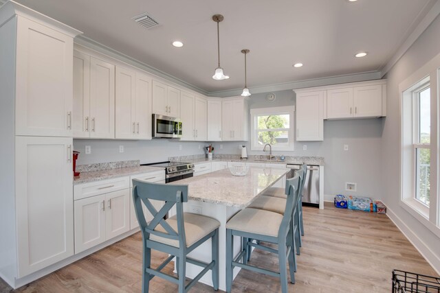 kitchen featuring white cabinetry, a kitchen bar, kitchen peninsula, stainless steel appliances, and light stone countertops