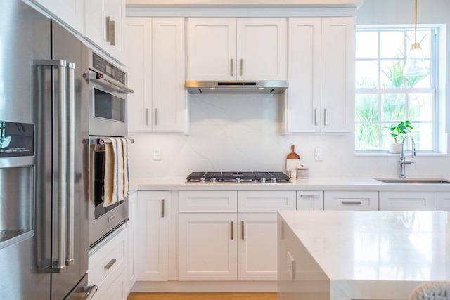 kitchen featuring appliances with stainless steel finishes, decorative light fixtures, sink, and white cabinets