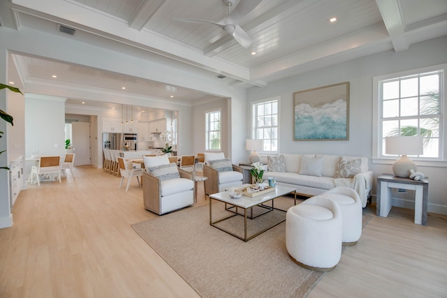 living room featuring plenty of natural light, light wood-type flooring, and beam ceiling